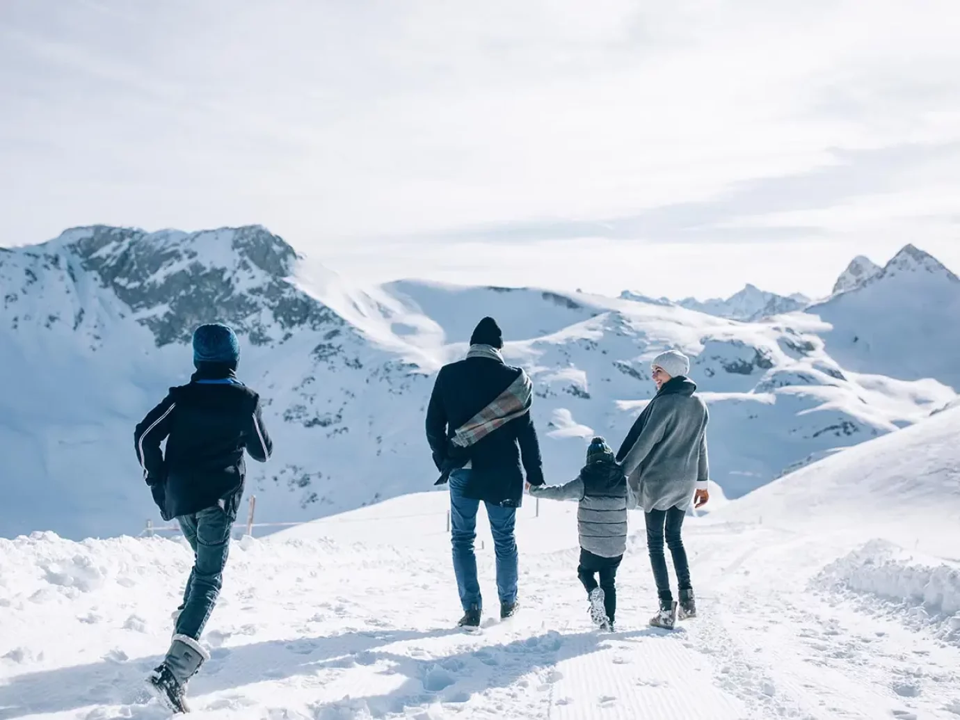 Familie mit Kinder beim Winterwandern in Lech am Arlberg, rundum verschneite Berge