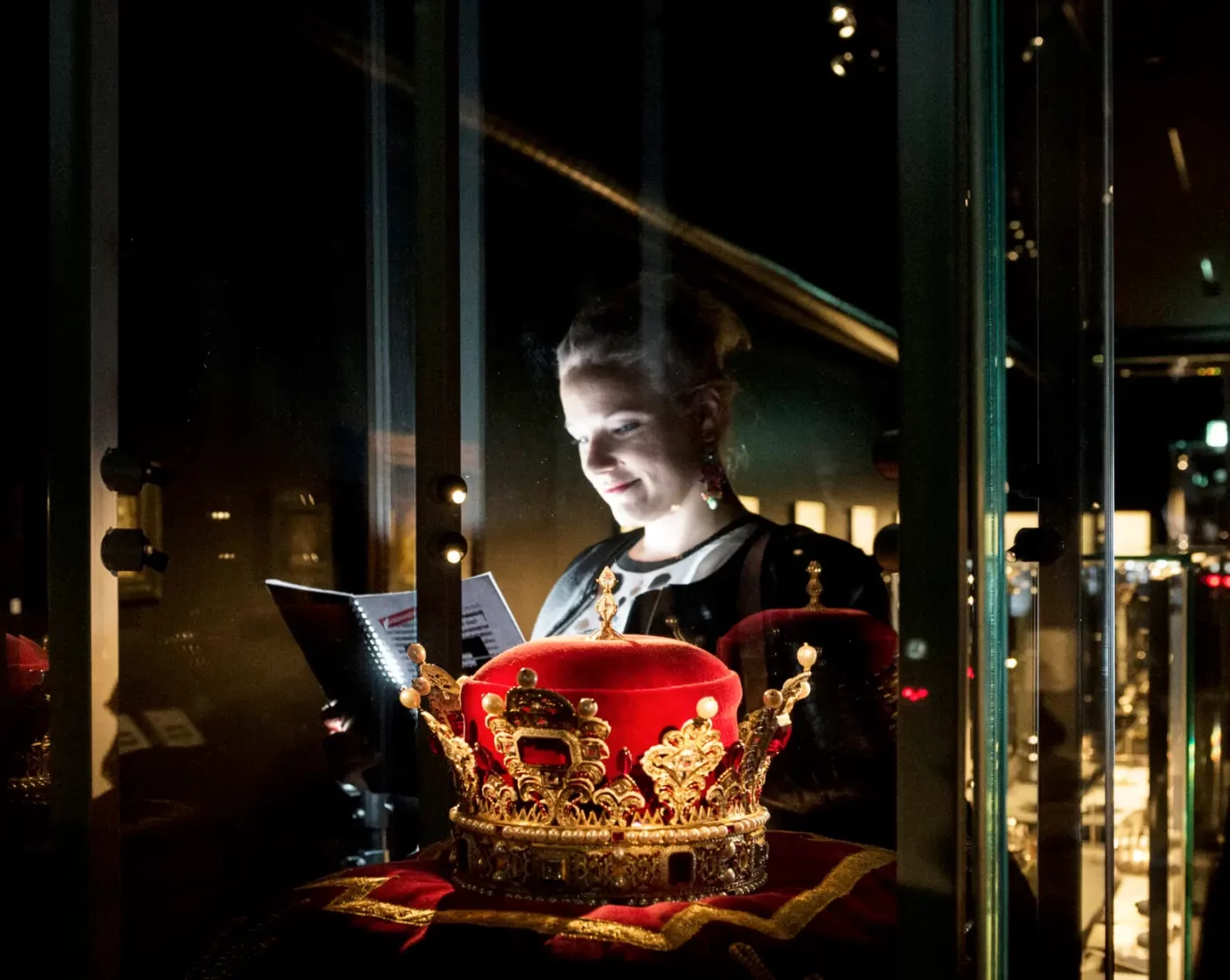 Die Frau sieht sich den Inhalt der Glasvitrine an in der Schatzkammer von Liechtenstein